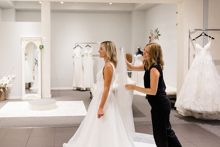 Woman helping customer with her wedding dress at Our Shop Bridal.