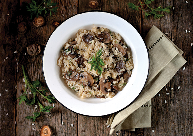 Risotto with mushrooms on an old wooden background. Rustic style.