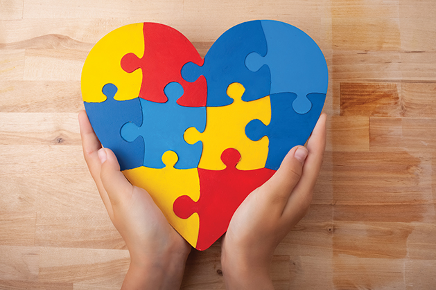 World Autism Awareness day, mental health care concept with puzzle or jigsaw pattern on heart with child's hands on wooden background