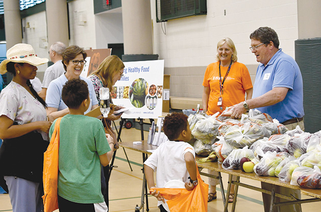 Food shelf volunteers chat with families about healthy fruit and veggies at a local gathering.