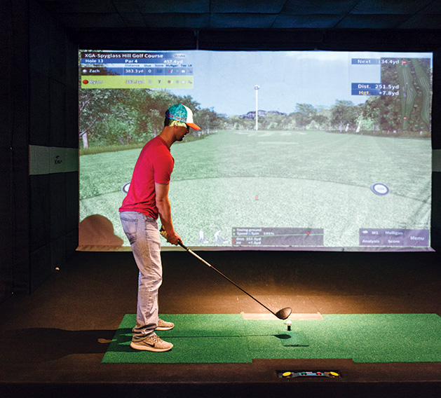 A golfer plays a virtual golf simulation at X-Golf in Woodbury.