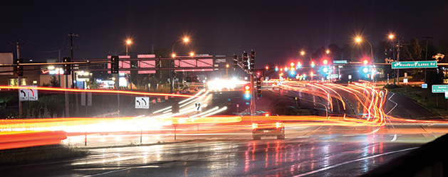A long exposure photograph shows the city lights and cars on Radio Drive in Woodbury.
