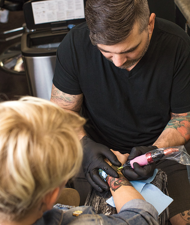 Aaron Michael tattoos a customer at Aloha Art Collective, a tattoo shop in Woodbury
