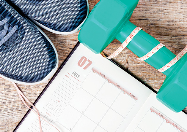 Exercise shoes, a free weight and a schedule tracking fitness goals.