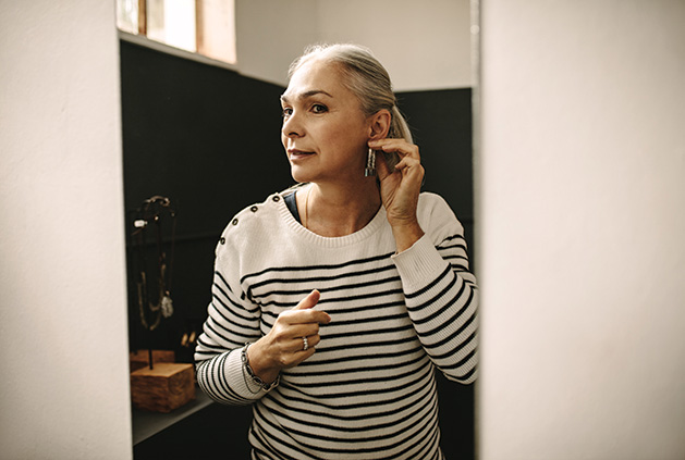 A senior woman checks her outfit in front of a mirror