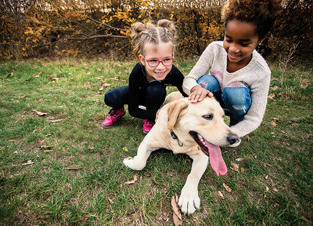 Two children play with a dog at Coco's Heart Dog Rescue Academy.