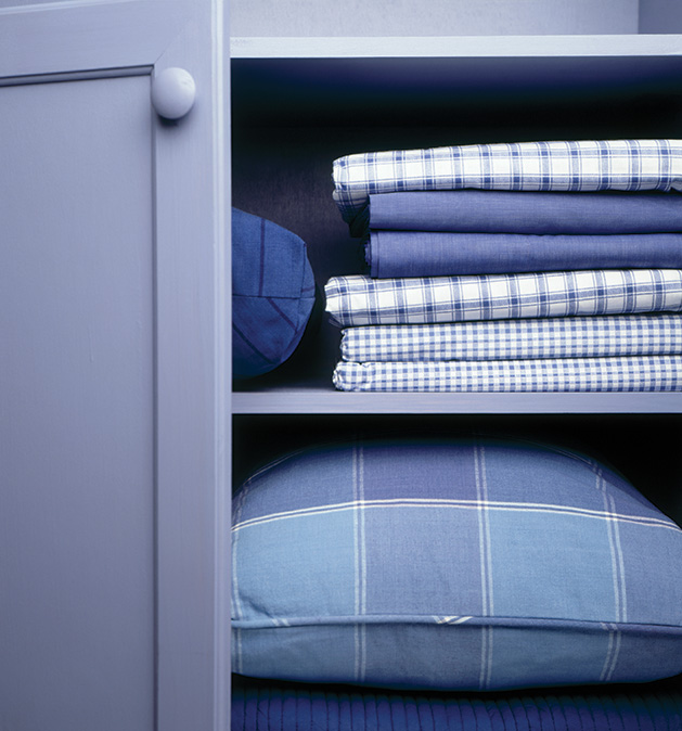 A pillow and sheets sit organized on shelves, ready for tidying up before a downsizing move.