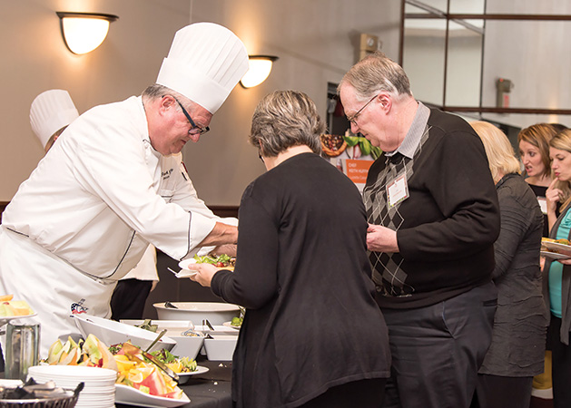 A chef prepares food for two guests at the Woodbury Community Foundation's Chef Fest.