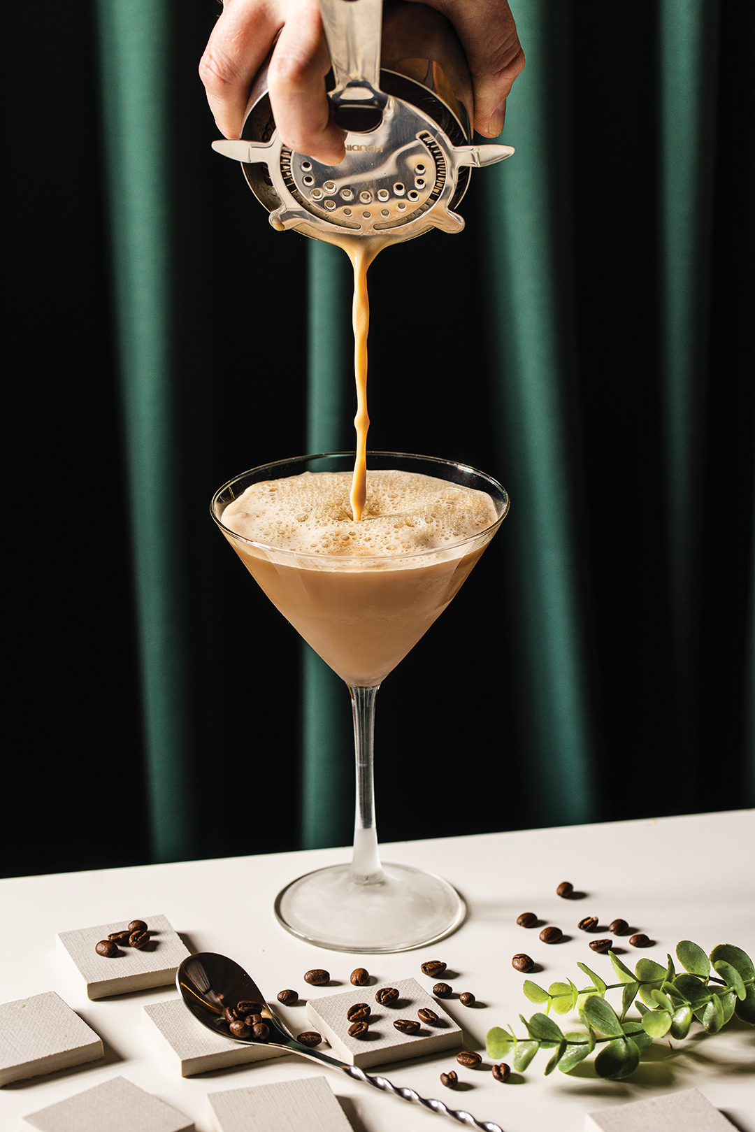 Hand pours an espresso martini into a glass.
