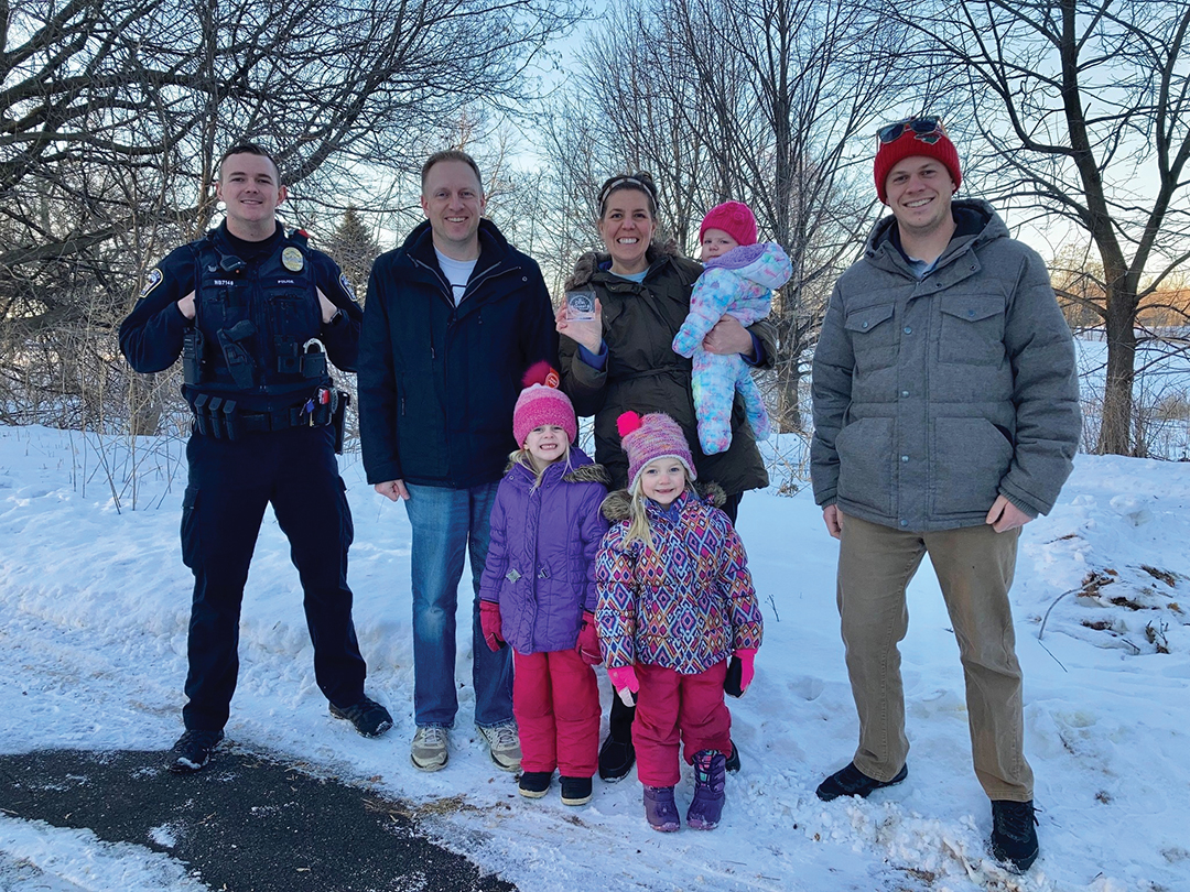 Participants of a past Winter Medallion Hunt celebrating their find with a member of the Woodbury Public Safety Department.