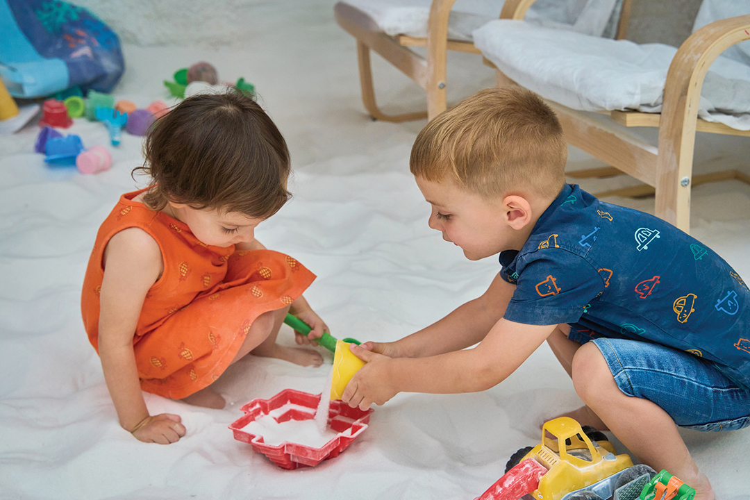 Two toddlers playing with toys in a salt cave during halotherapy session