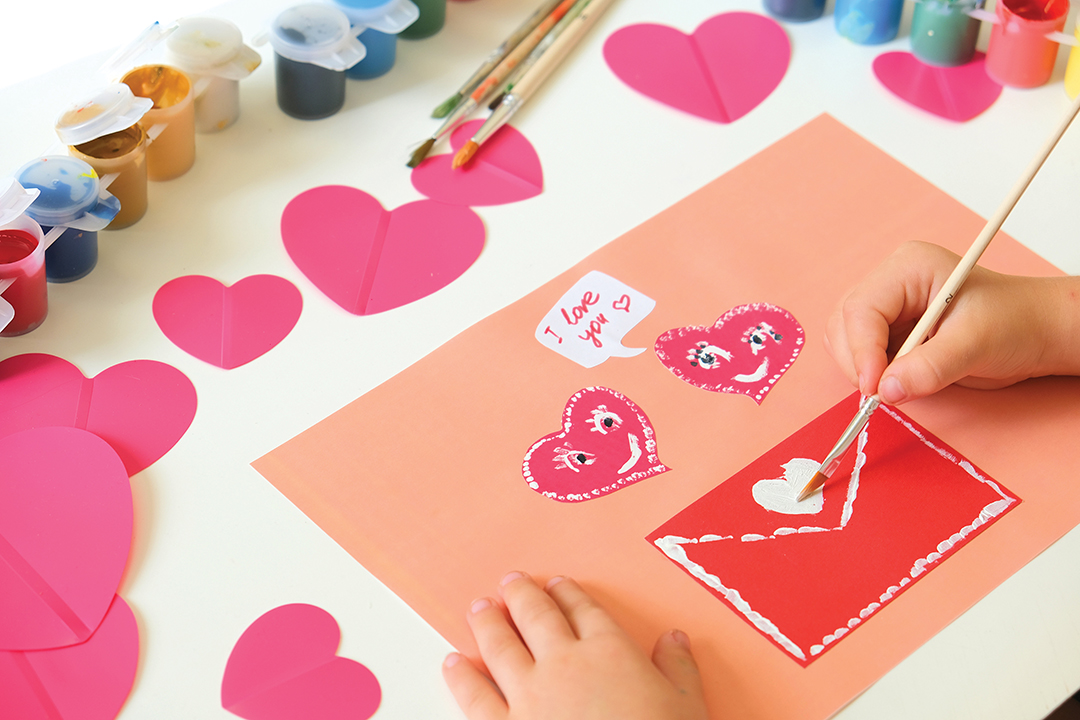 Child created homemade greeting card. A little girl painted and colored card with funny hearts. Gift for Mothers Day or Valentines day. Arts and crafts concept.