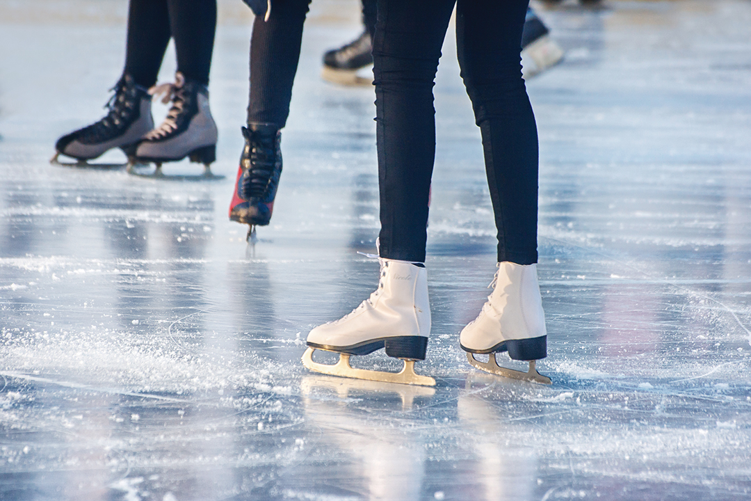 legs of boys and girls skating on winter day closeup