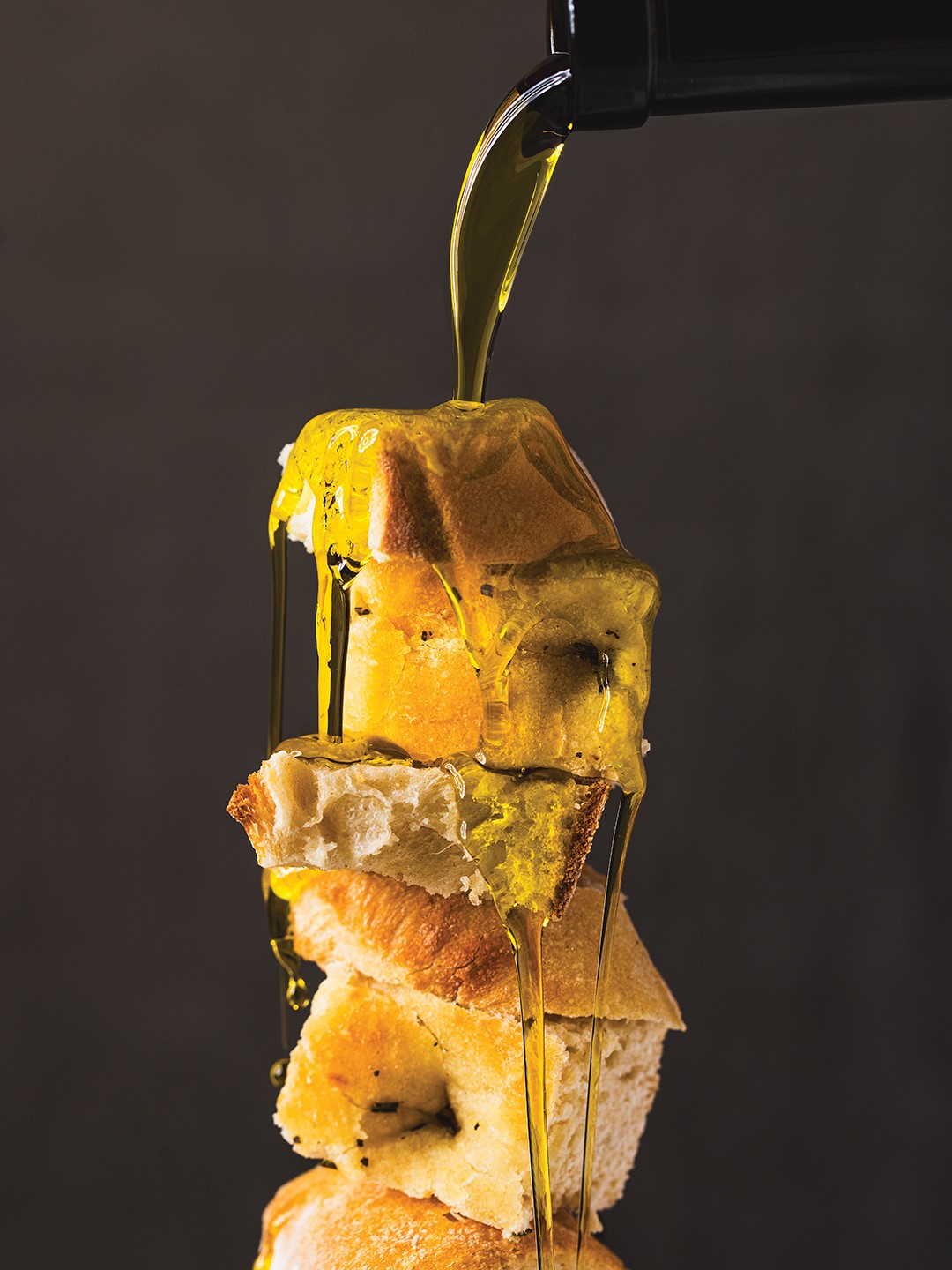 Olive oil being poured over chunks of bread.