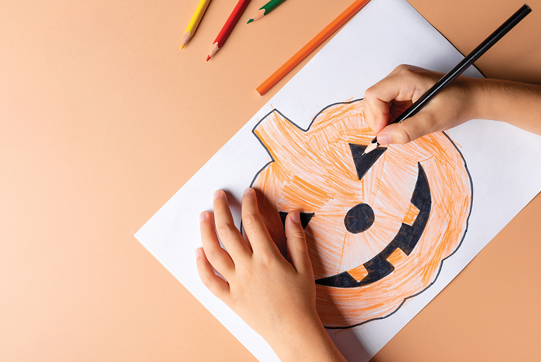 child making Halloween decorations from paper. Childrens crafts for the Halloween