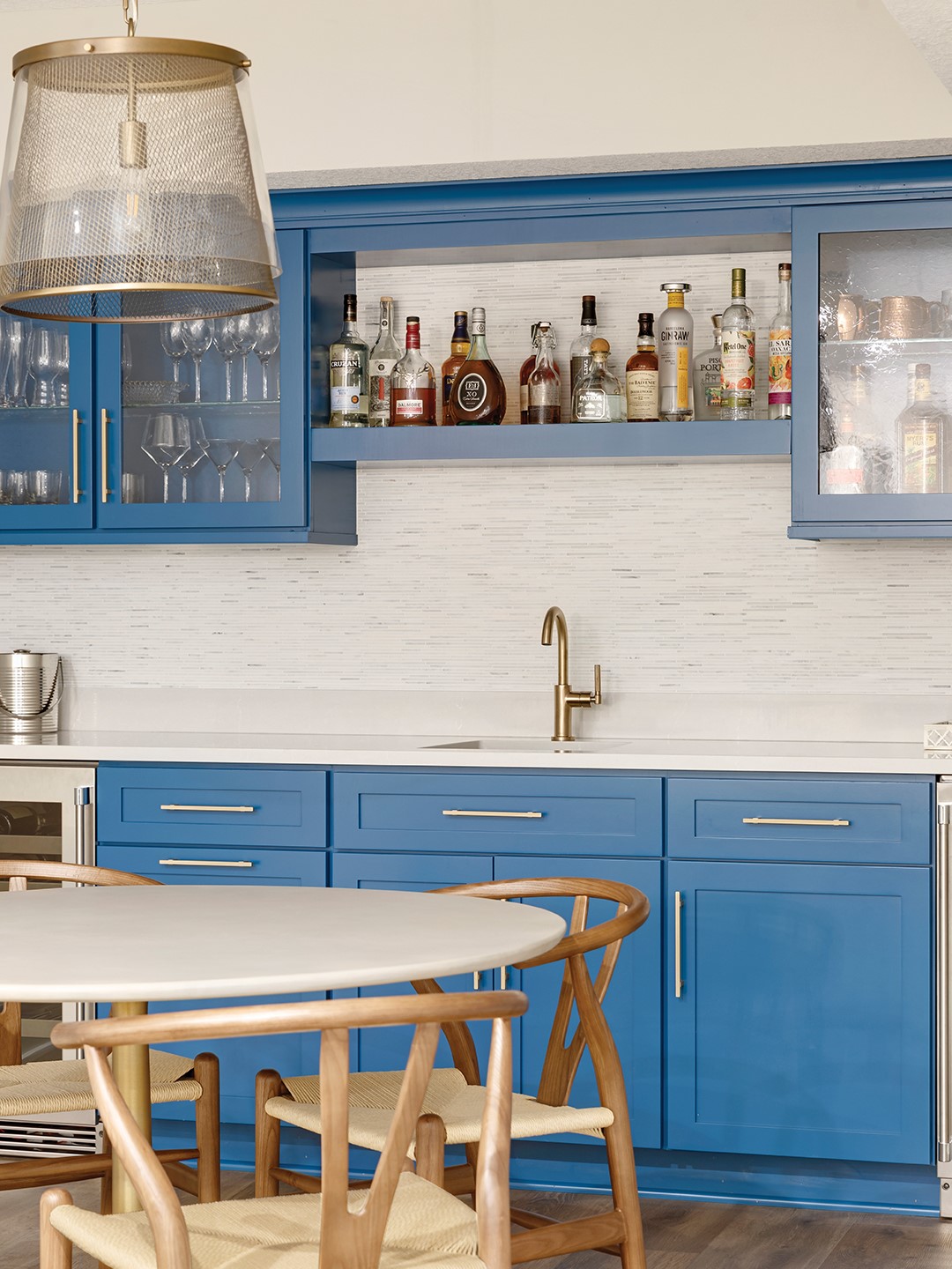 The downstairs area was revealed to be a worthy project; the homeowner explains that the staircase was opened, “which immediately stopped you from feeling like you were going into a cave,” she says. A bedroom was also added to the area. Designer Becca Hall adds, “We wanted the downstairs to feel like a place where the family could gather, entertain or unwind. Each area serves a purpose, from the cozy fireplace lounge to the vibrant blue bar to the playful billiards zone.” 